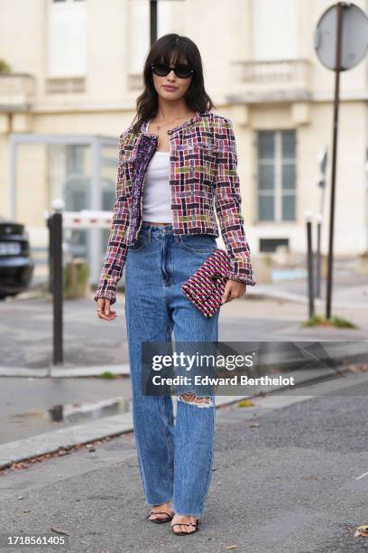 Sarah Ellen wears a colored checkered tweed jacket, a white tank top, blue ripped jeans, a Chanel clutch, outside Chanel, during the Womenswear...