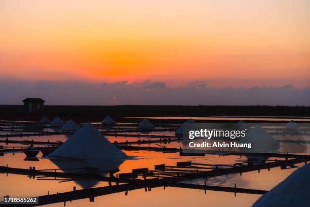 at the seaside salt pans in tainan, taiwan, the tranquil seawater reflects the orange-red evening glow during sunset. - tainan stock pictures, royalty-free photos & images