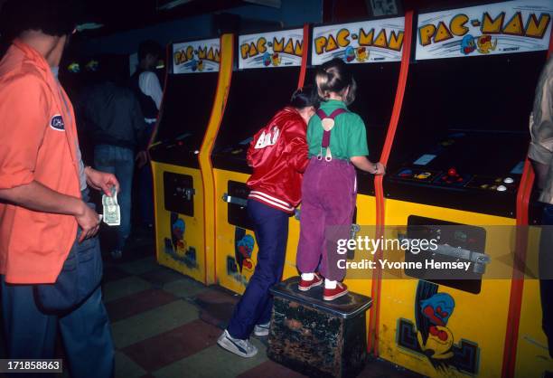 Young girls are photographed June 1, 1982 playing Pac-Man at a video arcade in Times Square, New York City.