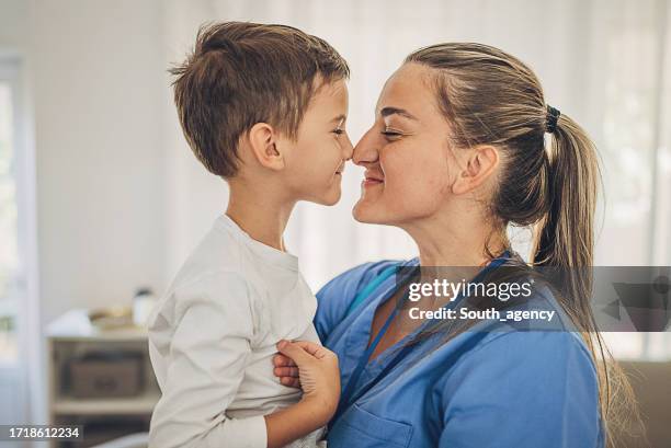 enfermera abrazada con su hijo en casa después del trabajo - cute nurses fotografías e imágenes de stock