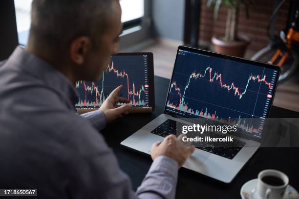 mann, der seine börseninvestition mit seinem laptop überprüft. - aktienschein stock-fotos und bilder