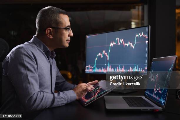 man checking his stock market exchange investment using his laptop computer at night. - etf stock pictures, royalty-free photos & images