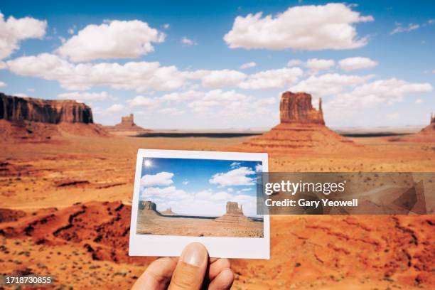 man holding an instant film photo of monument valley in front of the scene - terrain stock pictures, royalty-free photos & images