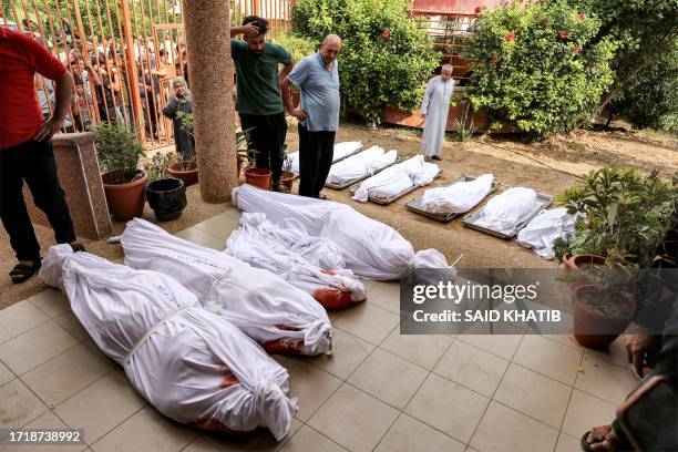 Graphic content / TOPSHOT - People gather in the courtyard of a morgue by the wrapped bodies of Palestinians killed in an Israeli air strike in Khan...