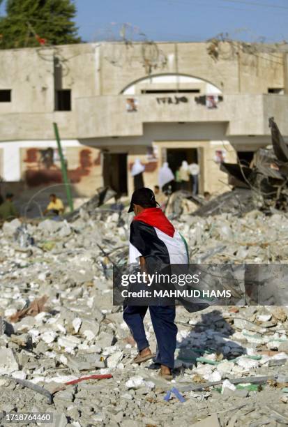 Palestinain boy wrapped with his national flag walks on the rubble in front of a destroyed synagogue in the former Israeli settlement of Kafar Darom,...