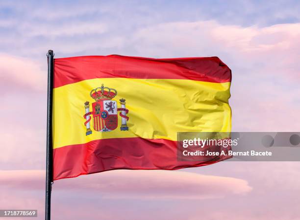 spain flag waving in the wind over a sunset sky. - drapeau espagnol photos et images de collection