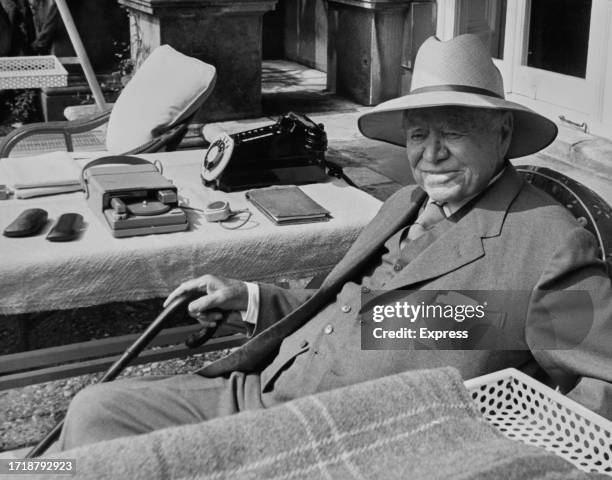 Canadian-British newspaper publisher Lord Beaverbrook , a tape recorder, a telephone and a notebook on the table beside him as he sits on the terrace...