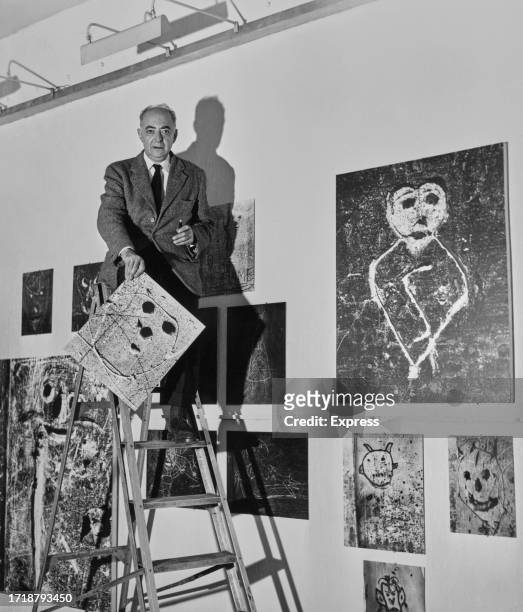 Hungarian-French artist and photographer Brassai stands atop a stepladder as he hangs his photographs for an exhibition at the Institute of...