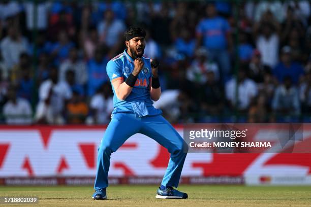 India's Hardik Pandya celebrates after taking the wicket of Afghanistan's Azmatullah Omarzai during the 2023 ICC Men's Cricket World Cup one-day...