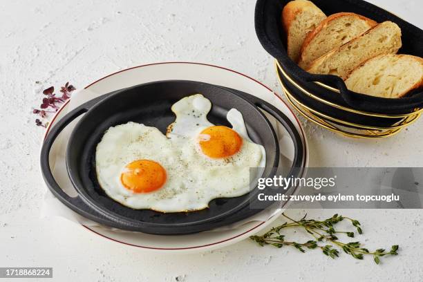 eggs served in a cast iron skillet with bread basket - heat stock pictures, royalty-free photos & images