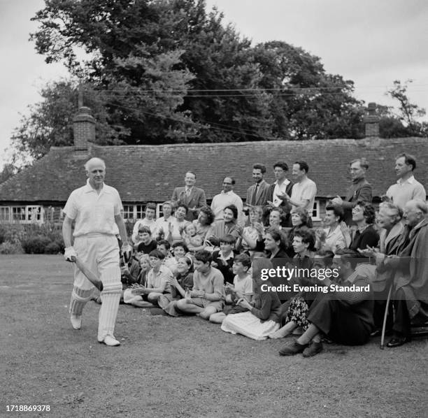 Poet Francis Meynell walks out in his cricket outfit while being clapped by a crowd of people, September 2nd 1958.
