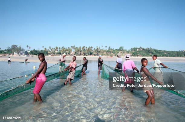 Members of a local family help to pull in fishing nets from the waters of the Indian Ocean off the beach of the coastal town of Vilankulo in...
