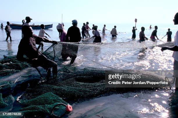 Members of a local family help to pull in fishing nets from the waters of the Indian Ocean off the beach of the coastal town of Vilankulo in...