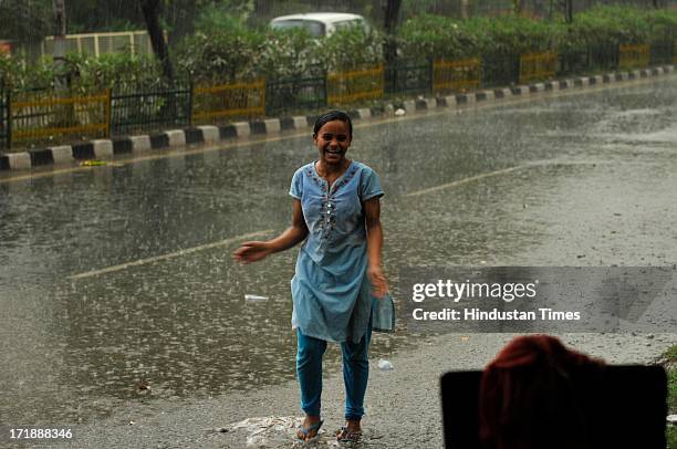 Girl enjoys during a heavy rainfall after a hot and humid afternoon on June 29, 2013 in Noida, India. Weather department forecast the country will...