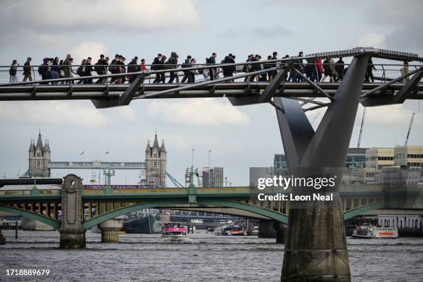 Members of the public walk across the Millennium Bridge on October 05, 2023 in London, England. The pedestrian bridge that spans the River Thames...