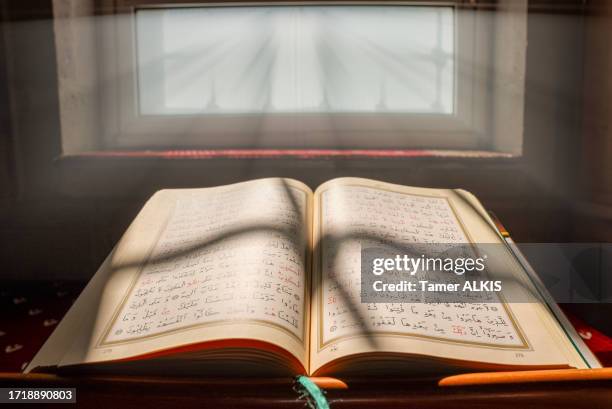 nahaufnahme des heiligen buches koran in der moschee, sonnenlicht wird auf den koran reflektiert - koran stock-fotos und bilder