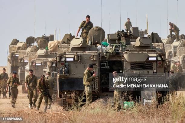 Israeli army soldiers stand near stationed Namer armoured personnel carriers at a position near the border with Gaza in southern Israel on October...