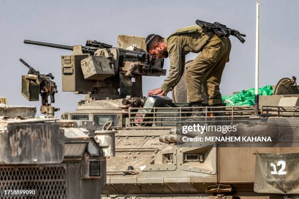 An Israeli army soldier stands atop a Namer armoured personnel carrier at a position near the border with Gaza in southern Israel on October 11,...