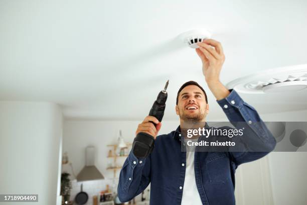 joven guapo instalando sensor de humo en su casa - sensor fotografías e imágenes de stock