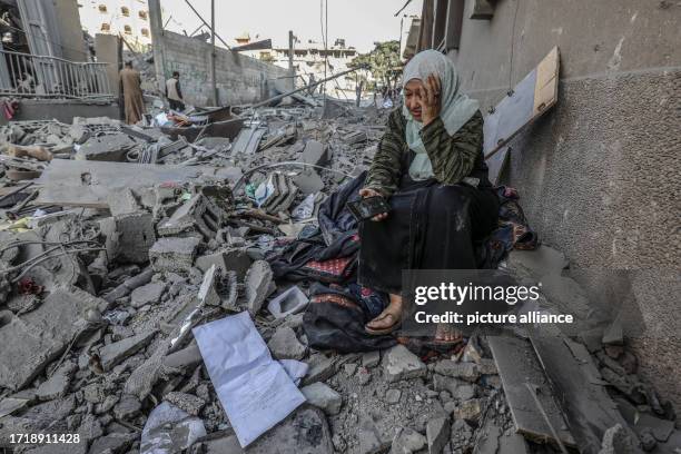 October 2023, Palestinian Territories, Rafah: A Palestinian woman sits on the ruins of her destroyed home following Israeli air strikes in Gaza City....