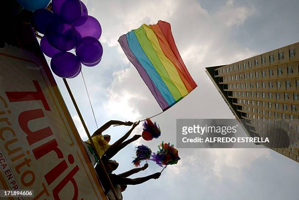 Woman waves a rainbow flag from on top of a bus during the 35th Gay Pride Parade along Reforma Avenue in Mexico City on June 29, 2013. AFP...