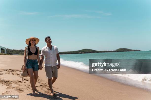 couple walking while talk along the beach - latina swimsuit stock pictures, royalty-free photos & images