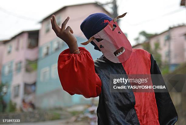 Child from the Mangueira favela de Rio de Janeiro plays and dances wearing a mask called 'folhas do reis' on June 29, 2013 on the eve of the final of...