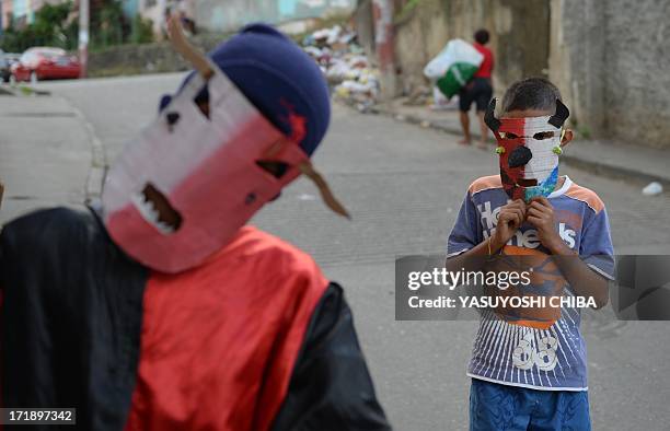 Children from the Mangueira favela of Rio de Janeiro plays and dances wearing masks called 'folhas do reis' on June 29, 2013 on the eve of the final...