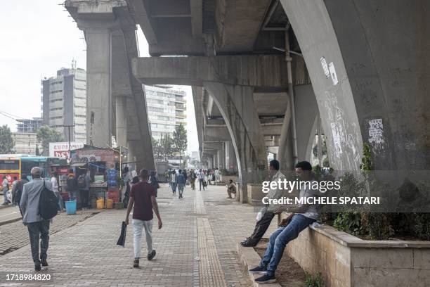 People walks past a public bus stop next to Meskel Square in Addis Ababa on October 11, 2023.