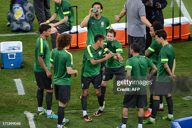 Brazil's forward Neymar jokes with teammate Bernard during a training session at the Maracana stadium in Rio de Janeiro, on June 29, 2013 on the eve...