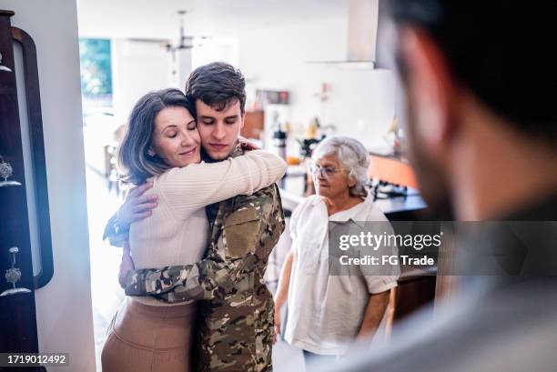 army soldier embracing his mother after his return home - military camouflage pattern stock pictures, royalty-free photos & images