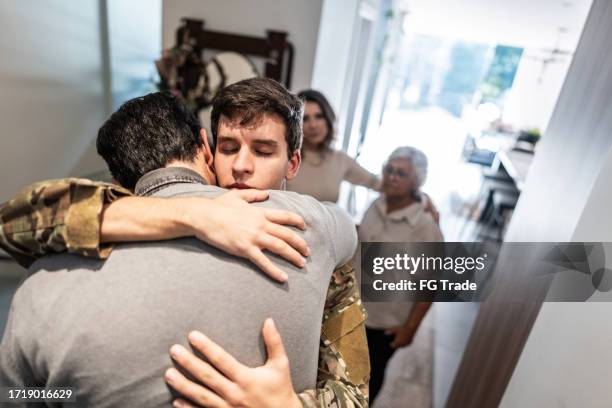 soldato dell'esercito che abbraccia suo padre dopo il suo ritorno a casa - dispiegamento di forze armate foto e immagini stock