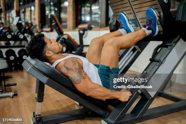 muscular man exercising on thigh workout machine in gym - quadriceps muscle stock pictures, royalty-free photos & images
