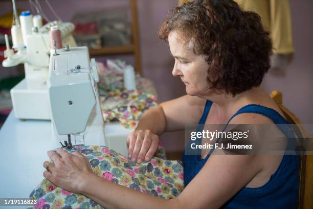 middle aged woman working with a sewing machine - thimble stock pictures, royalty-free photos & images