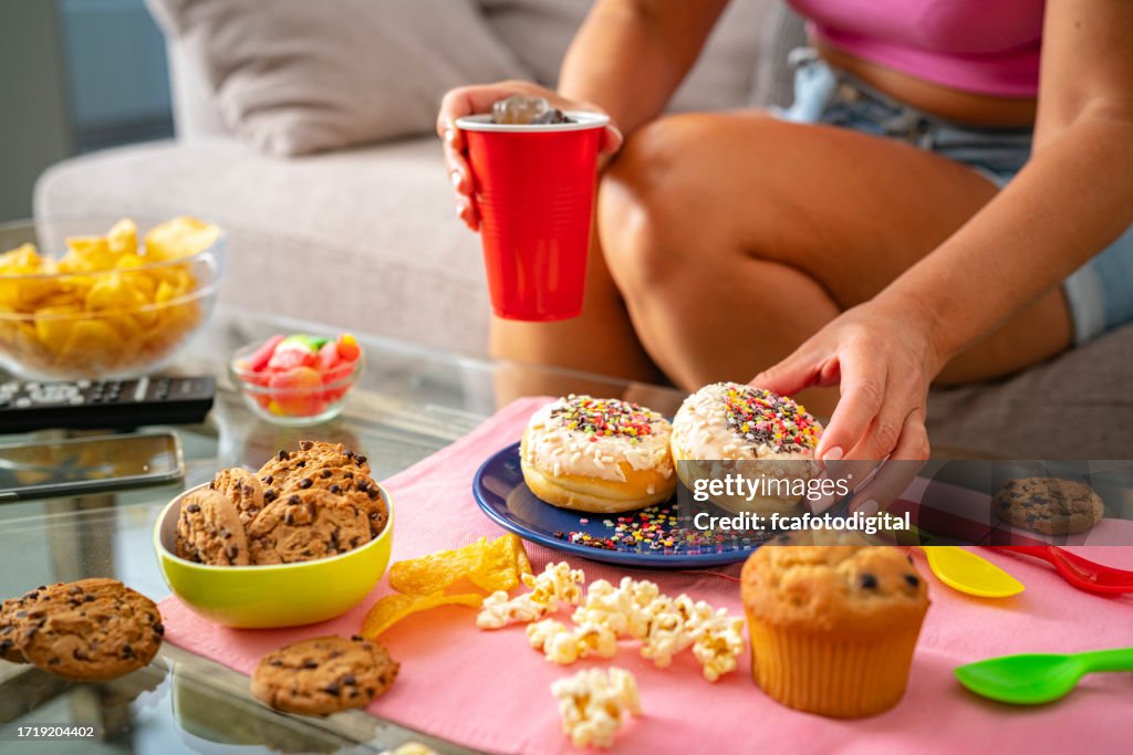 Konzept der ungesunden Ernährung. Nahaufnahme einer Frau, die Donut isst und Cola trinkt.