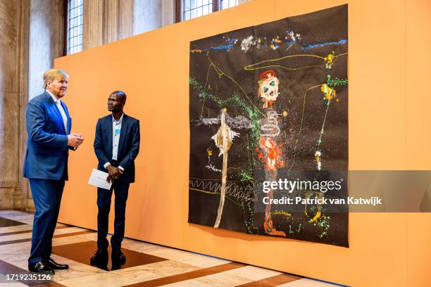 King Willem-Alexander of The Netherlands speaks with artist Thierry Oussou during the Royal Prize for Free Art award ceremony at the Royal Palace on...