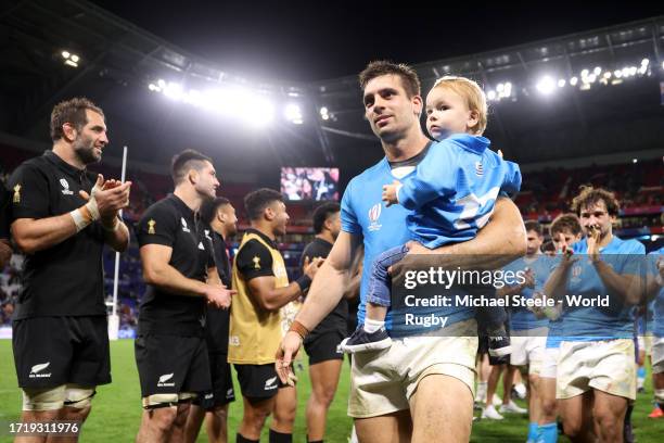 Andres Vilaseca of Uruguay carries a child as he leaves the field whilst the players of New Zealand give the players of Uruguay a guard of honour at...