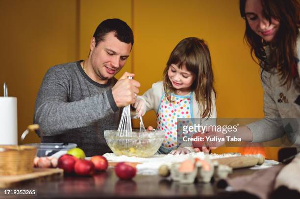 real family in a kitchen making a pie toghether. - apple cake stock pictures, royalty-free photos & images