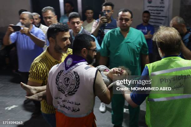 Graphic content / Medics transport an injured Palestinian girl into Al-Shifa hospital in Gaza City following an Israeli airstrike on October 11 as...