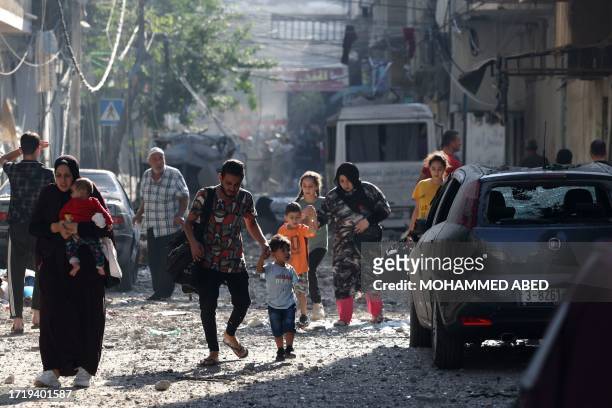 Graphic content / Palestinians evacuate a neighbourhood in Gaza City on October 11 as raging battles between Israel and the Hamas movement continued...