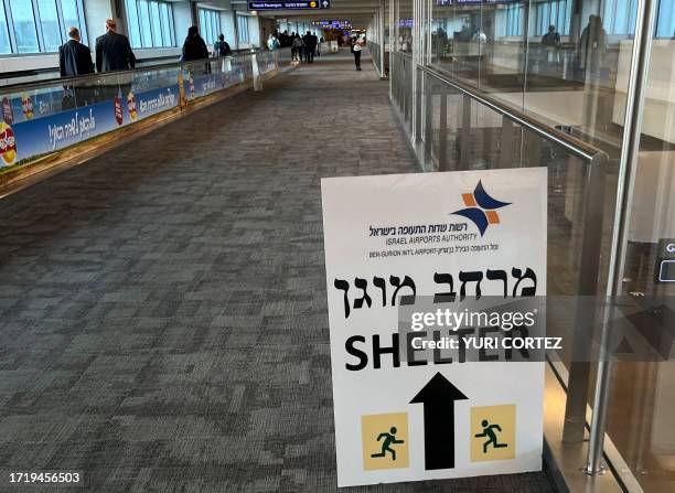 Sign informing passengers about the location of rocket shelters is set-up in a hallway as travelers arrive at Ben Gurion International Airport near...