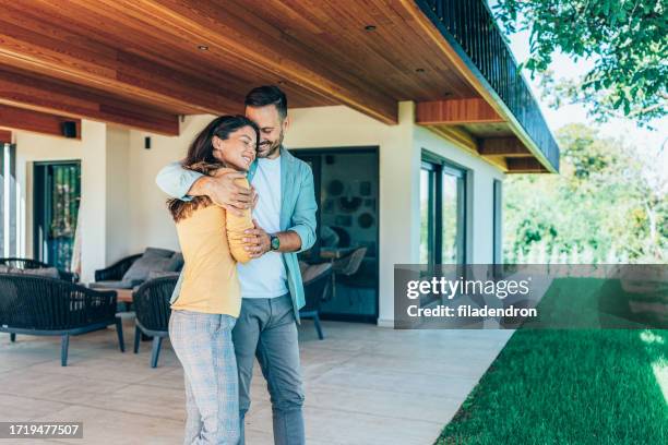 embraced couple in front of their new house - home sweet home stock pictures, royalty-free photos & images