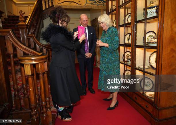 Helena Bonham Carter shows Queen Camilla a poetry book, with William Sieghart, founder and CEO of the Forward Arts Foundation during a reception...