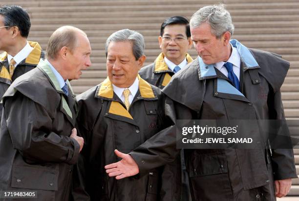 President George W. Bush extends his hand to greet Russia's President Vladimir Putin and Thailand's Prime Minister Surayud looks on as they arrive to...