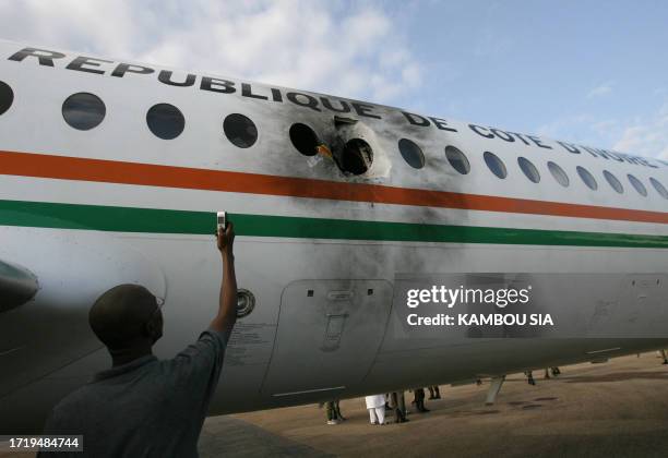 Man takes a snapshot of the damaged fuselage of Ivory Coast Prime Minister Guillaume Soro 's plane at Bouake airport after it was hit by a rocket....