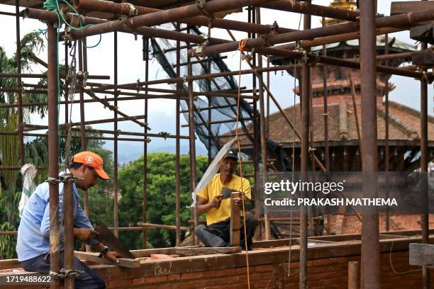 In this photograph taken on June 22 labourers chisel wood at a reconstruction site in the Patan Durbar Square of Lalitpur district on the outskirts...