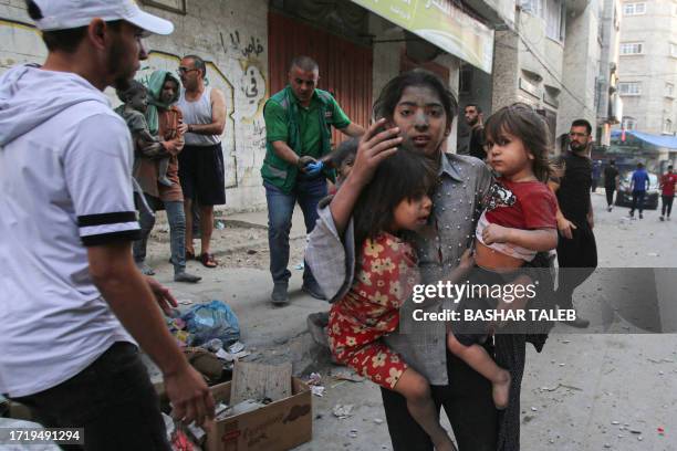 Palestinian girl holds two children as she stands on a street in Gaza City on October 12, 2023 as raging battles between Israel and the Hamas...