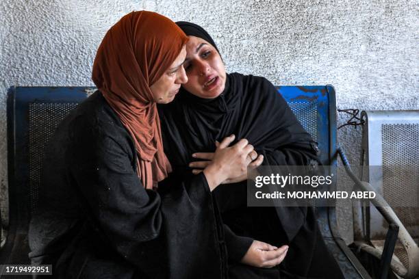 Graphic content / A woman comforts another mourning outside the morgue of al-Shifa hospital in Gaza City on October 12, 2023. Thousands of people,...