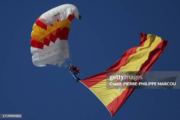 Spanish paratrooper waves a giant Spanish National flag during the Spanish National Day military parade in Madrid on October 12, 2023.