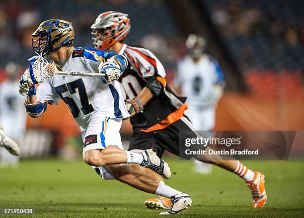 Peet Poillon of the Charlotte Hounds drives past Jeremy Sieverts of the Denver Outlaws during a Major League Lacrosse game at Sports Authority Field...